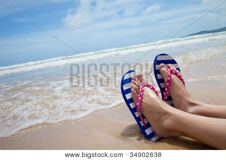 สาวขาในรองเท้า flipflop สีสันบนชายหาดทะเล