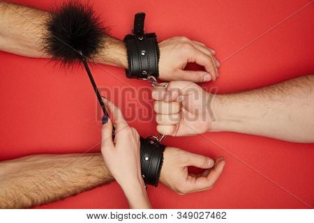 Cropped View Of Men And Woman With Handcuffs And Feather Tickler Isolated On Red