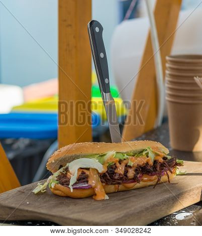Delicious Pulled Pork Sandwich Served With A Knife On A Wooden Plate.