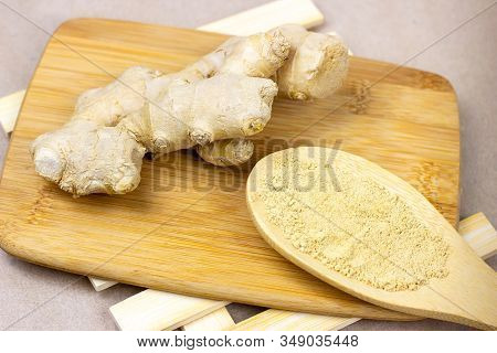 Fresh Raw Yellow Ginger Root With Ground Dry Powder In Wooden Spoon And On Wood Background.