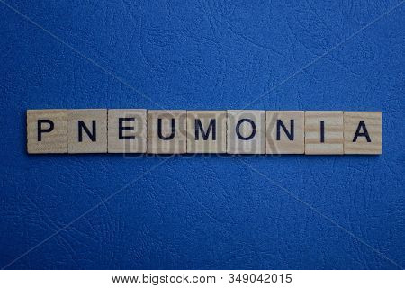 Gray Word Pneumonia From Small Wooden Letters On A Blue Table