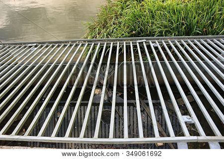 Metal Galvanised Grill Covering A Notch Weir On The Outlet Pipe From A Lake With The Lake And Margin