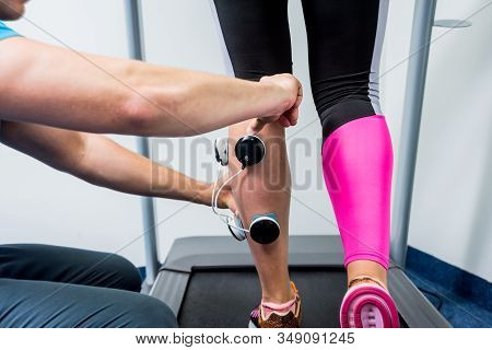 Physical Therapist Install Electrostimulator On The Muscles Of The Legs.