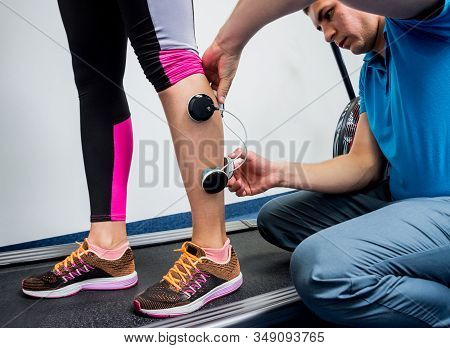 Physical Therapist Install Electrostimulator On The Muscles Of The Legs.