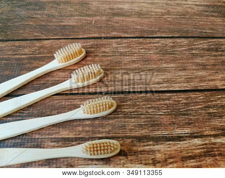 A Family Set Of Four Wooden Toothbrushes On Wooden Background With Copy Space