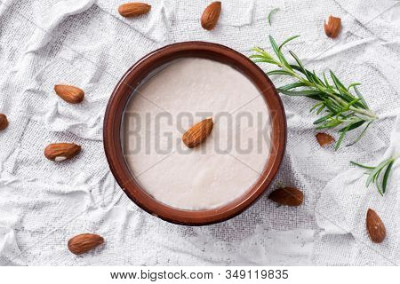 high angle view of an earthenware bowl with menjar blanc, a dessert made with almonds and sugar typical of Catalonia, Spain, on a white textured surface