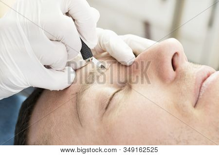 Young Man Microblading Procedure To Improve The Condition Of A Mans Eyebrows In A Beauty Salon.