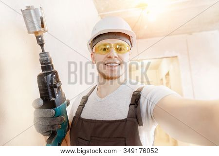 Builder Worker Man Makes Selfie Photo With Safety Glasses And White Helmet With Pneumatic Hammer Dri