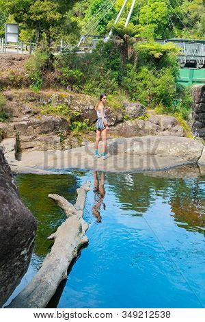 Rock Pool With Log In Water And Attractive Girl Standing On Other Side At Mclaren Falls Tauranga New
