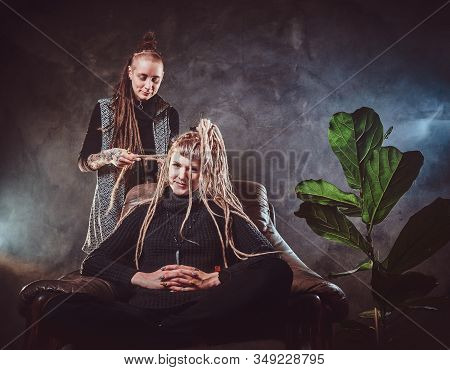 In A Misty Room Full Of Smoke Dread Master Is Making A Dreadlocks For Blond Girl.