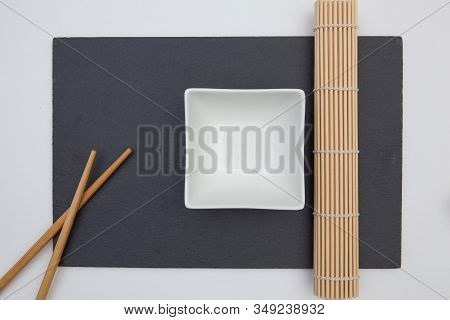 Rectangular Slate Plate With Chopsticks, Ceramic Plate, Bamboo Mat For Sushi On The White Table.
