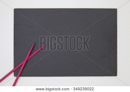 Rectangular Slate Plate With Purple Chopsticks For Sushi On The White Table. Food Design.