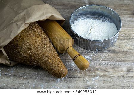 A Loaf Of Bread Along With Rocking For The Dough In A Craft Bag Stand On A Wooden Table, Next To It 