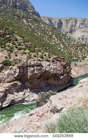 A Large Slab Of Granite Sticks Up From The Embankment Of The Bighorn River As It Winds Its Way Throu