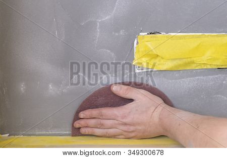 Sandpaper Held In Grip Of Mans Hand, Refinishing Piece Of Custom Stucco Wall