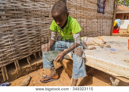 Bissau, Guinea-Bissau - January 5, 2020: portrait on an African Kid and his dog, in rural Guinea-Bissau