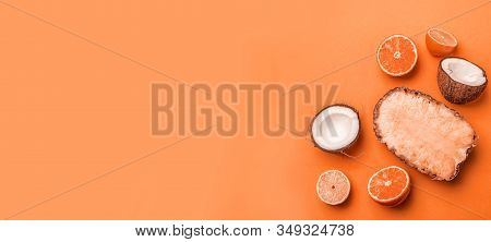 Top View Of Assorted Exotic Fruits On An Orange Background. Pineapple, Coconut, Orange And Lemon Hal