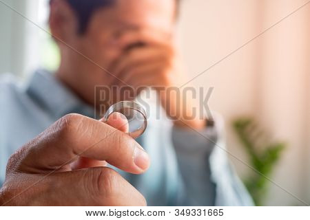 Image Of Husband Crying Sadly Holding A Wedding Ring After An Argument With His Wife And Deciding To