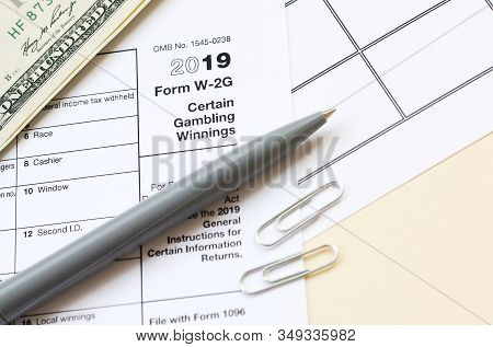 Irs Form W-2g Certain Gambling Winning Blank Lies With Pen And Many Hundred Dollar Bills On Calendar