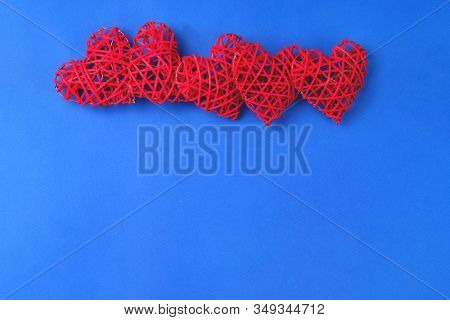 Beautiful Wicker Red Hearts On The Cornflowerblue Background. St Valentines Concept With Copy Space.