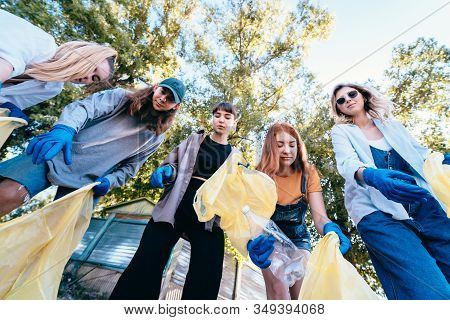 Group Of Activists Friends Throw A Lot Of Garbage In A Bag. Bottom-up Shooting