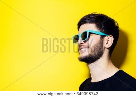 Studio Portrait Of Young Smiling Hipster With Aqua Menthe Sunglasses On Orange Background.