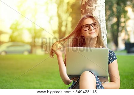 Daydreaming About Future. Pensive Woman Teenage Girl Female With A Laptop Sitting Near A Tree On A G