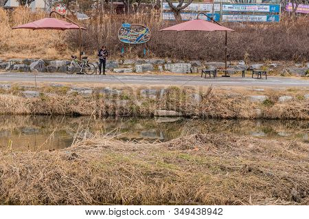 Daejeon, South Korea; January 28, 2020: Unidentified Man Standing Next To Bicycle Using Cellphone On