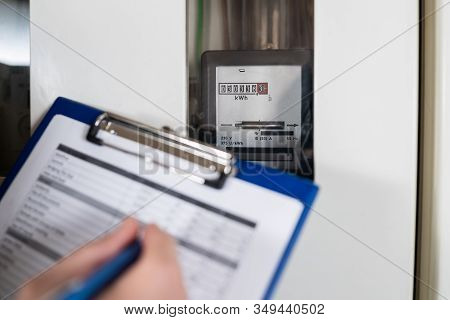 Close-up Of A Technician Hand Writing Reading Of Meter On Clipboard