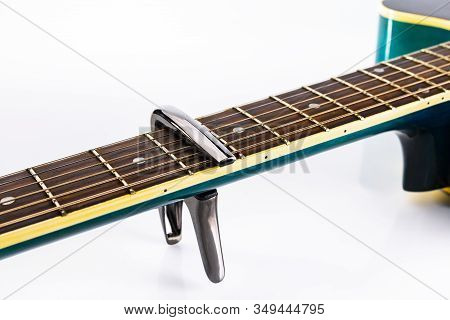 A Capotasto On A Fretboard Of Acoustic Guitar, On A White Background, Close-up, Side View.
