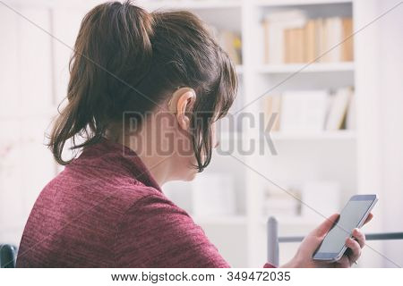 Deaf woman wearing hearing aid and using smartphone