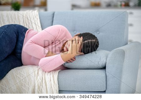 Full-figured Young Woman In A Pink Shirt Lying On A Sofa