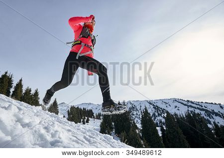 Trail Runner Woman Running In Winter Mountains On Snow. Dynamic Running Downhill On Trail Woman Athl