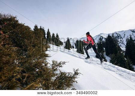 Trail Runner Woman Running In Winter Mountains On Snow. Dynamic Running Uphill On Trail Woman Athlet