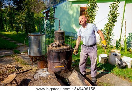 Man Is Manually Turning Lever To Mix Fruit Marc In Boiler Of Homemade Distillery Made Of Copper, Mak