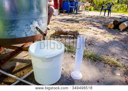 Man Takes A Sample Of Freshly Distillated Liquor, Alcohol In The Laboratory Graduated Cylinder.