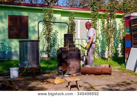 Man Is Manually Turning Lever To Mix Fruit Marc In Boiler Of Homemade Distillery Made Of Copper, Mak