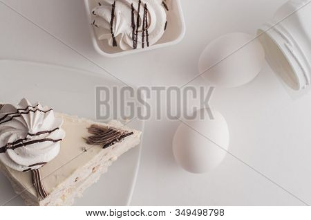White Cake With Merinques And Cream And Eggs On The Kitchen Table