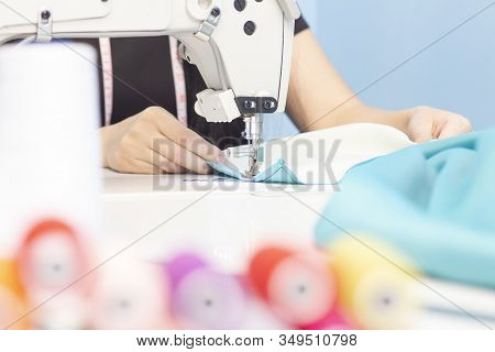 Sewing Studio. Seamstress Sewing On A Sewing Machine Close-up. A Set Of Items For Needlework: Thread