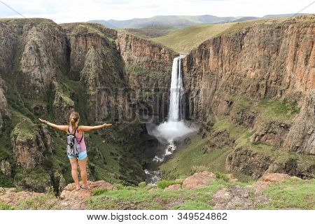 Woman Standing Next To Stunning Waterfall Running Down A Steap Canyon