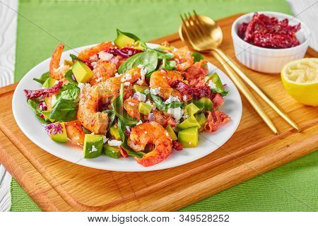Shrimp Avocado Spinach Salad With Sun-dried Tomatoes, Crumbled Cheese, Red Onion On A Plate On A Woo