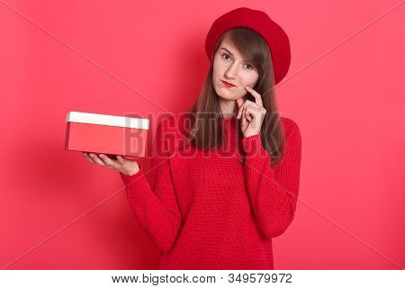 Image Of Tender Attractive Sweet Young Female Wearing Bright Red Sweater And Hat, Touching One Cheec