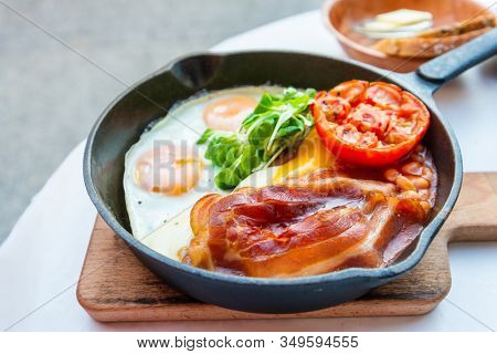Grilled toasts served with beans, scrumbled eggs and sausage for an English breakfast