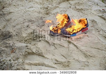 Burning Sports Sneakers Or Gym Shoes On Fire Stand On Sandy Beach Coast. Athlete Burned Out. Physica