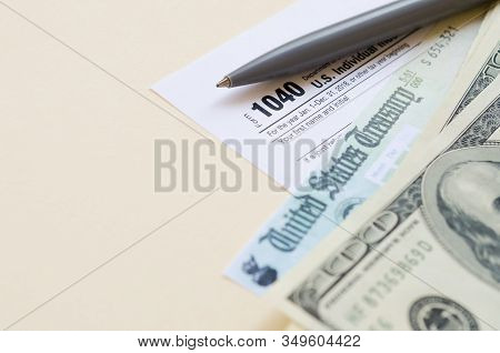 1040 Individual Income Tax Return Form With Refund Check And Hundred Dollar Bills On Beige Backgroun