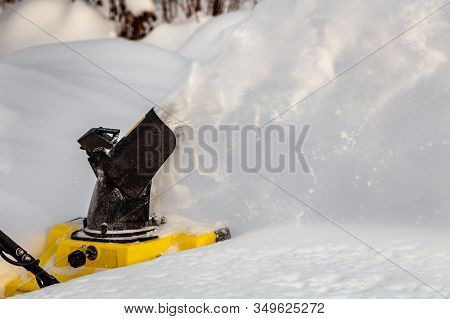 Man Is Brushing White Snow With The Yellow Electric Snow Thrower In A Winter Garden
