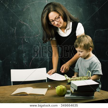 Little Cute Boy In Glasses With Young Real Teacher, Classroom Studying At Blackboard School Kido
