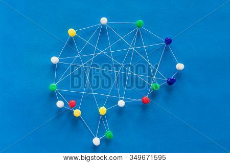 Neural Network Concept, Multi-colored Pins And White Threads Create An Image Of The Brain On A Blue 