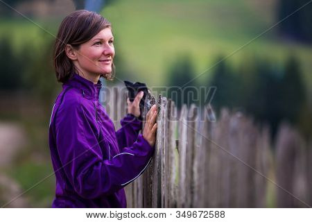 Beautiful Woman In A Purple Coat Standing By The Fence