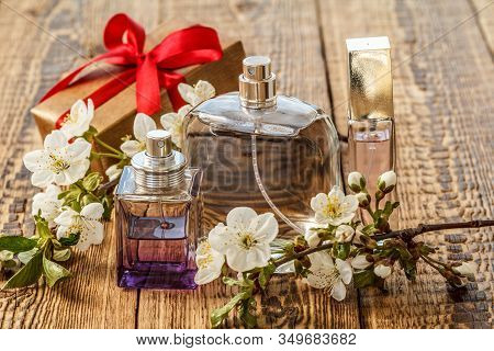 Gift Box And Bottles Of Perfume With Flowering Branch Of Jasmine On The Wooden Background. Concept O